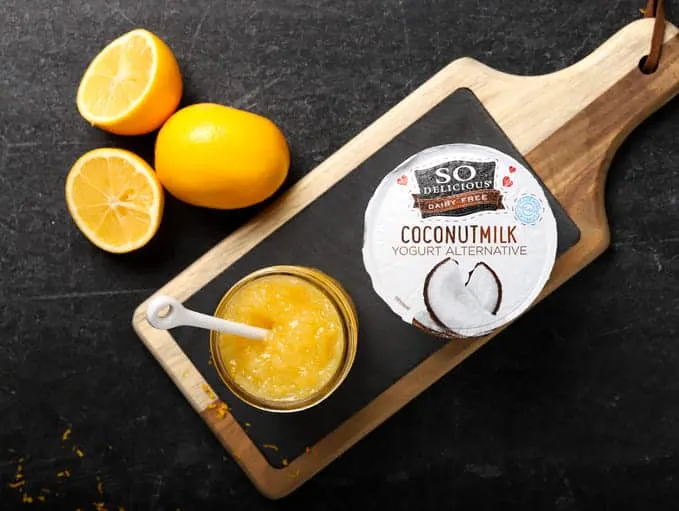 Vegan lemon curd in mason jar with spoon on cutting board with coconutmilk yogurt alternative