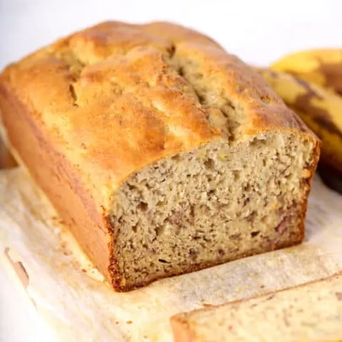 Close up photo of gluten free banana bread on wood cutting board and parchment paper