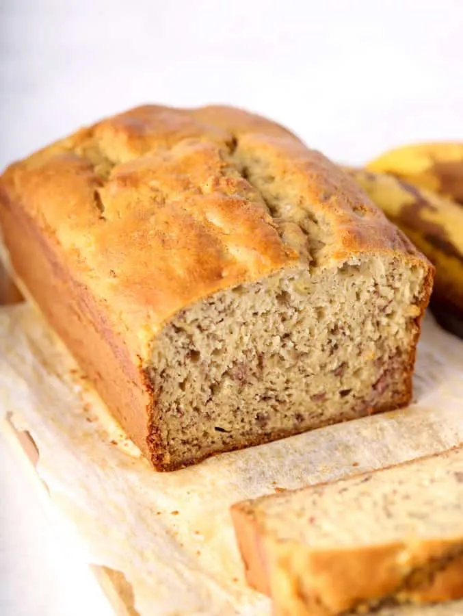 Close up photo of gluten free banana bread on wood cutting board and parchment paper