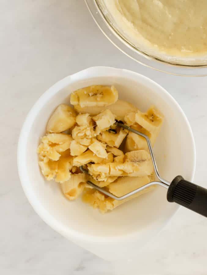 Ripe bananas being mashed with potato masher for gf banana bread