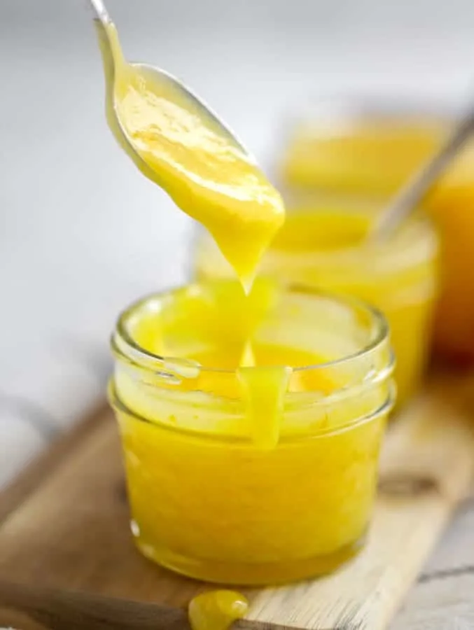 Spoon with lemon curd dripping into mason jar