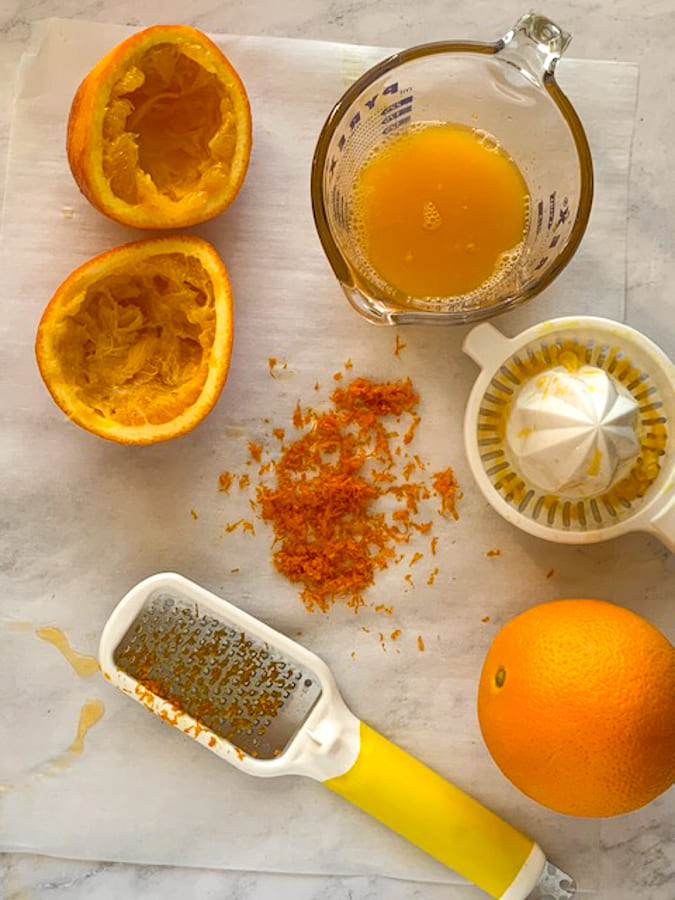 whole oranges and squeezed oranges and zest on parchment paper