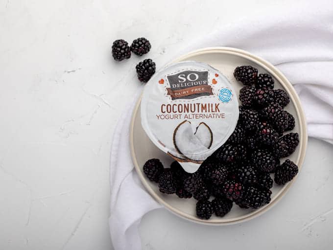 Blackberries on white round plate with so delciious yogurt alternative
