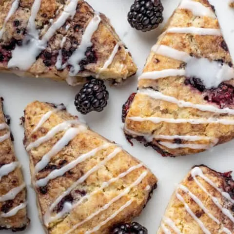 overhead photo of vegan blackberry scones with icing drizzle on marble board