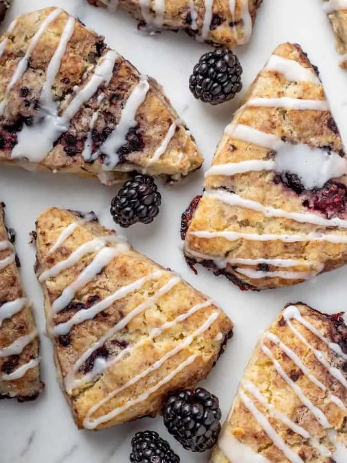 overhead photo of vegan blackberry scones with icing drizzle on marble board