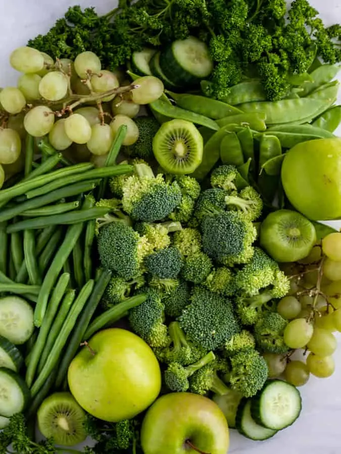 variety of green fruits and vegetables on marble board