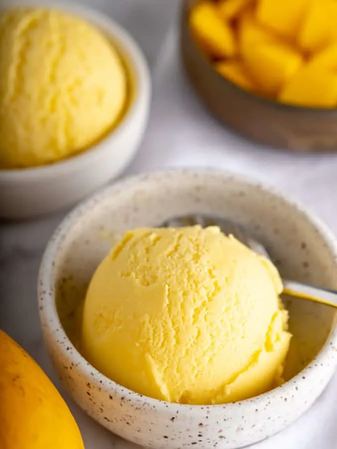 homemade mango gelato in pottery bowl with spoon