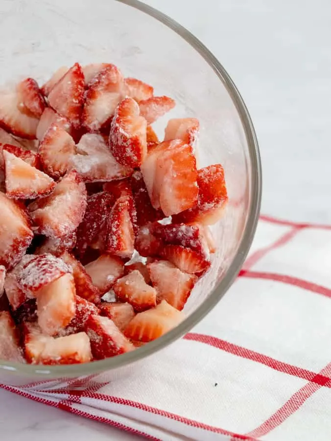 cut strawberries tossed in gf flour in glass bowl