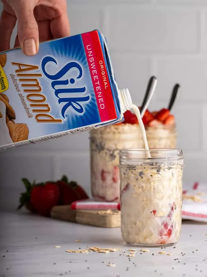 silk almond milk pouring into mason jar of overnight oats