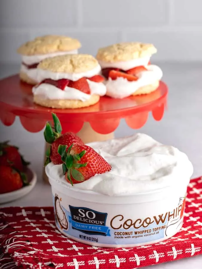 tub of Cocowhip with two strawberries on red and white towel