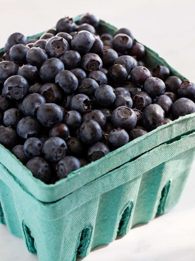 Teal cardboard container filled with fresh blueberries