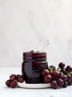 mason jar filled with grape jam with fresh grapes