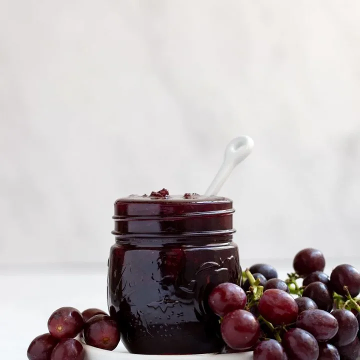 mason jar filled with grape jam with fresh grapes