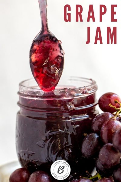 Spoonful of grape jam dipping into mason jar of jam