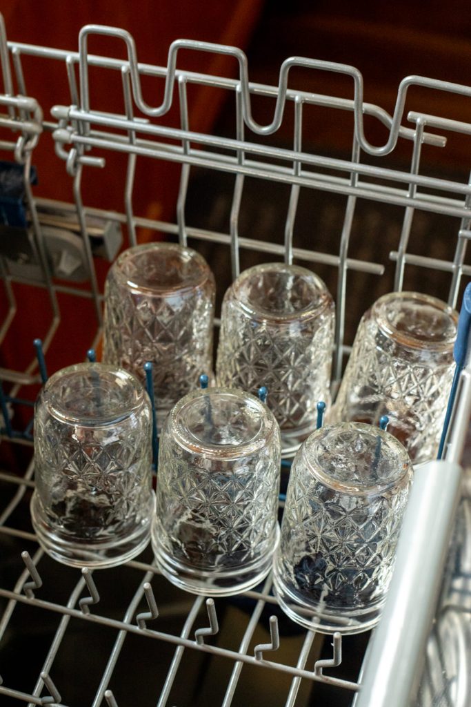 six glass mason jars on top rack of dishwasher