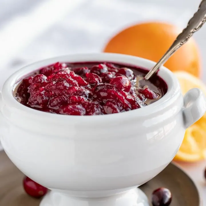 white bowl of cranberry sauce with oranges and silver spoon