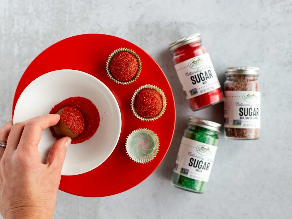 Hand rolling chocolate truffle in a bowl of red sanding sugar