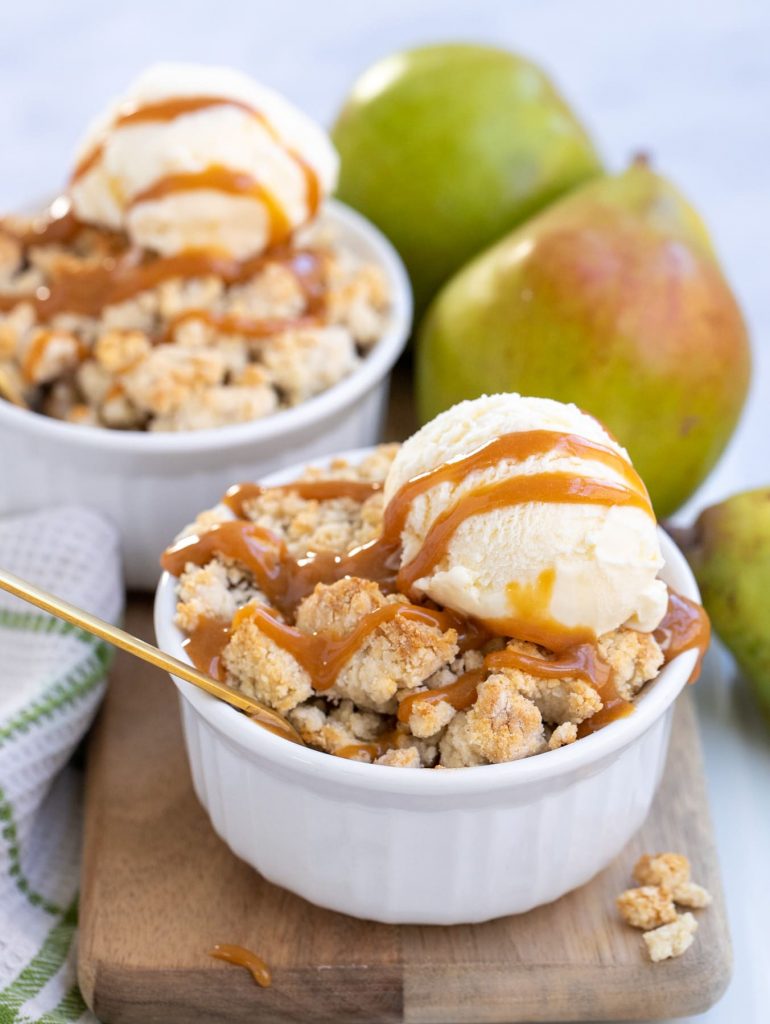 Two individual servings of pear cobbler with ice cream and caramel sauce