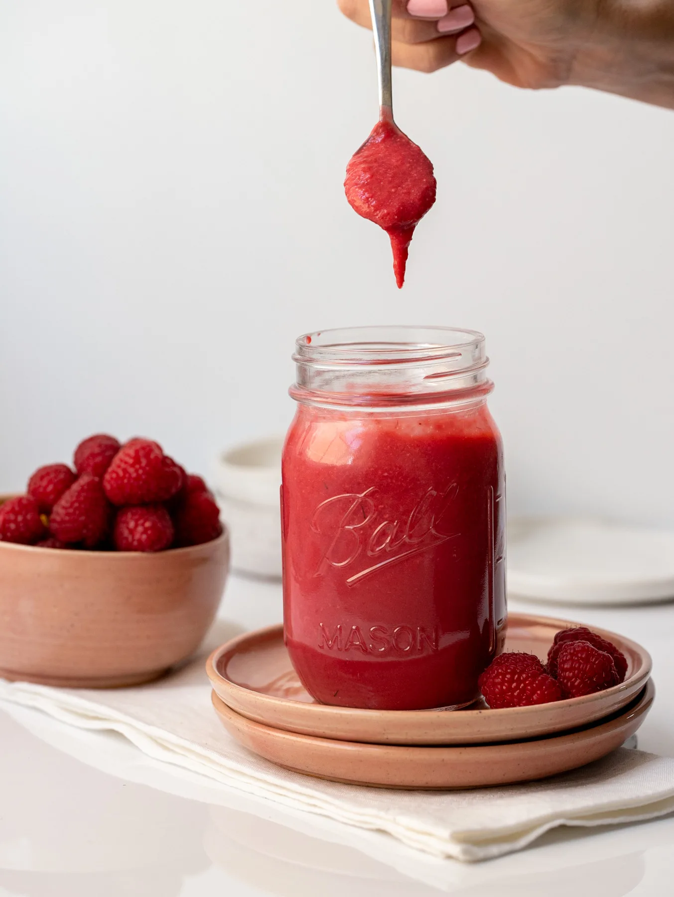 mason jar filled with raspberry curd and one spoonful lifted above jar