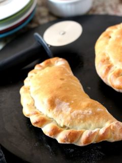 Baked homemade calzone on black pizza baking stone