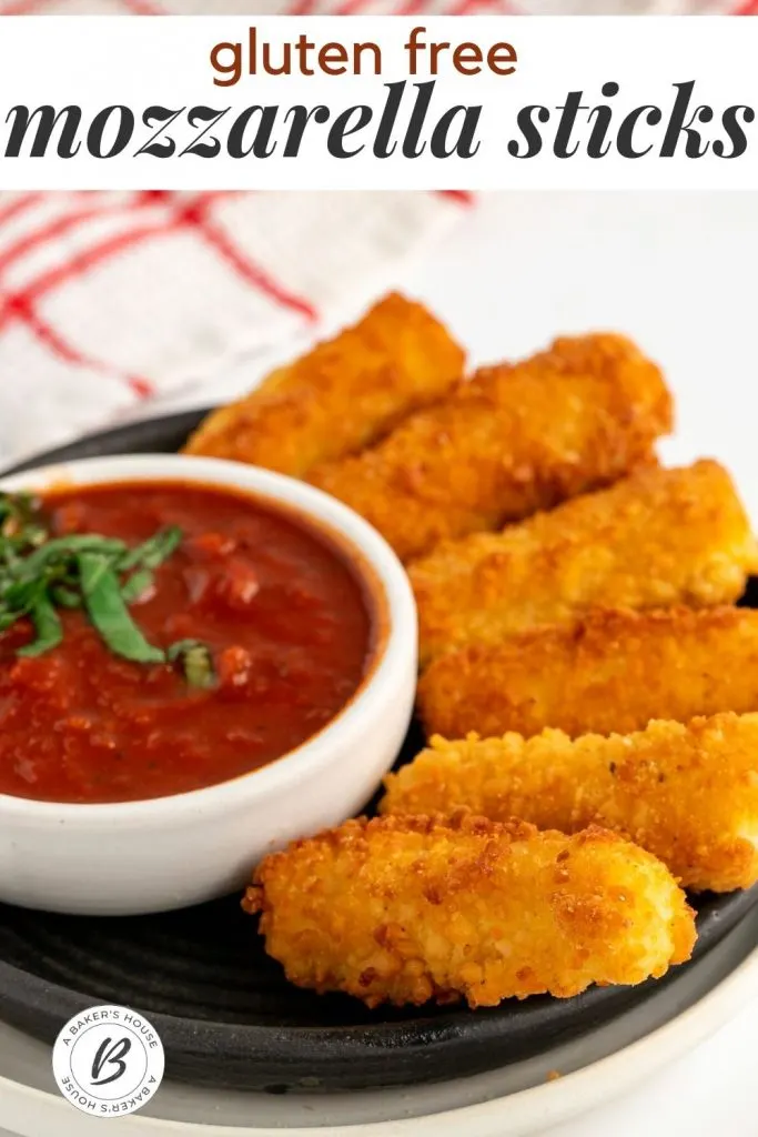 gluten free mozzarella sticks on black plate with tomato dipping sauce in white bowl