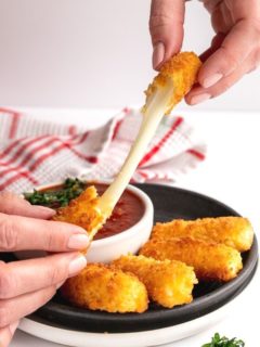 two hands pulling apart mozzarella sticks gooey cheese