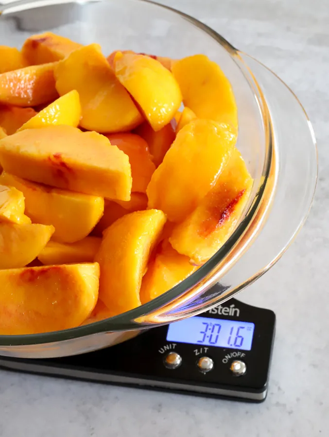Three pounds of peeled and sliced peaches on a kitchen scale