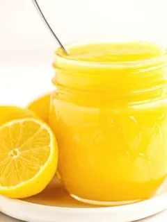 sliced fresh lemon next to mason jar filled with yellow lemon curd