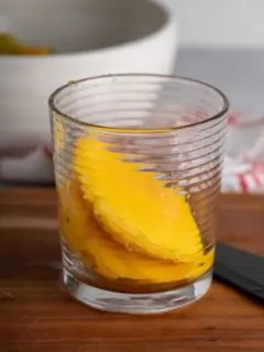 mango halves in a glass on a cutting board