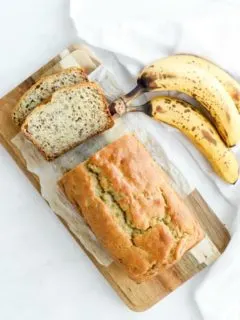 two slices of gf banana bread and loaf on wood cutting board