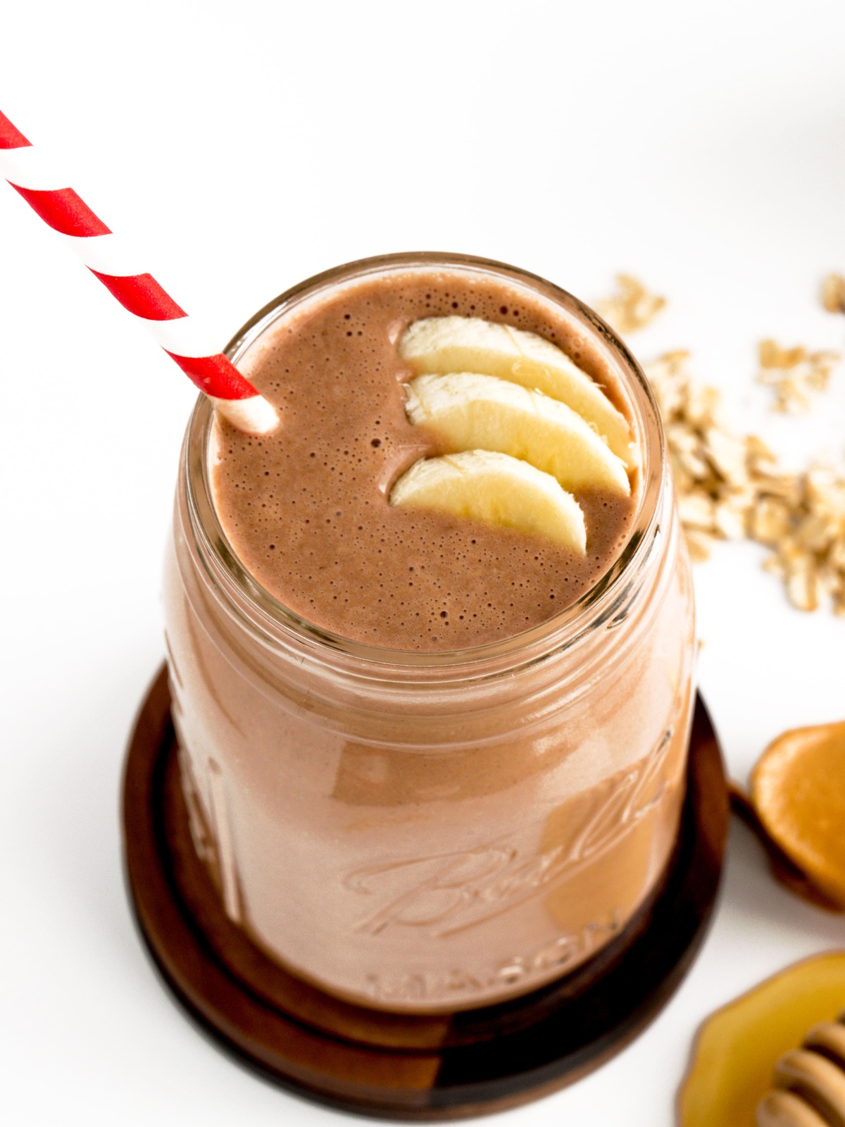 chocolate peanut butter oat smoothie with bananas and red and white straw