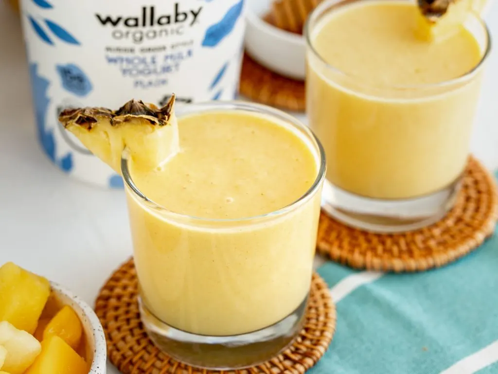 two glasses of pineapple mango smoothie with wallaby yogurt in background