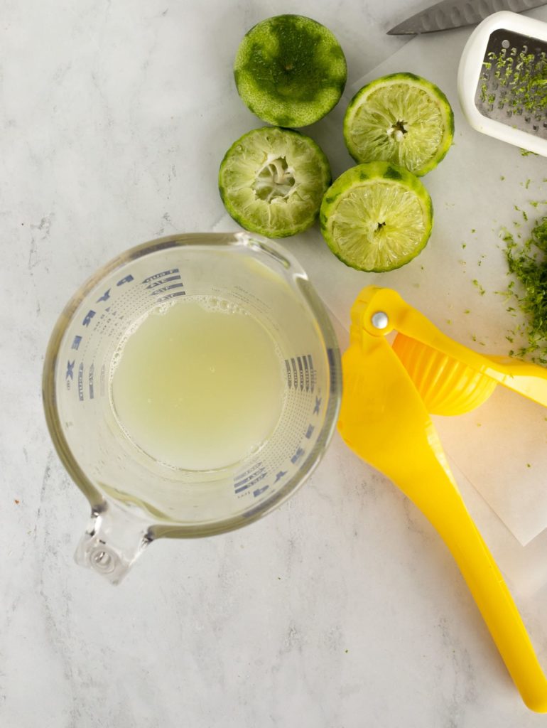 lime juice, limes, and lime squeezer on parchment paper