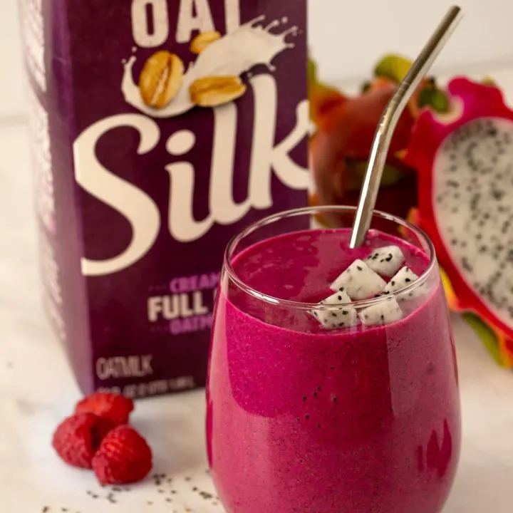 Dragon fruit smoothie in a glass with silver straw and Silk Oatmilk