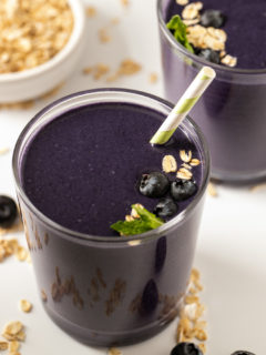 blueberry smoothie in single glass on white surface