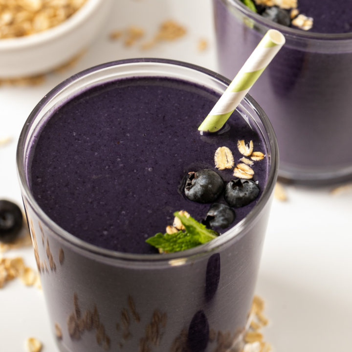 blueberry smoothie in single glass on white surface