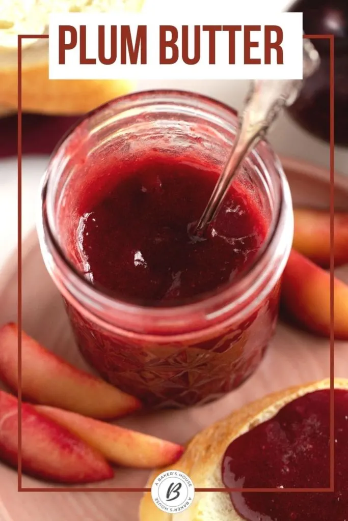 plum butter in a jar with silver spoon and fresh plums on surface